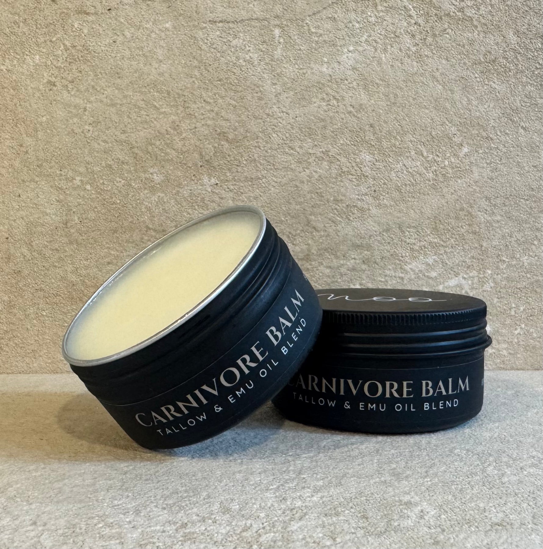 2 Black Tins by Moo Organics labeled Carnivore Balm