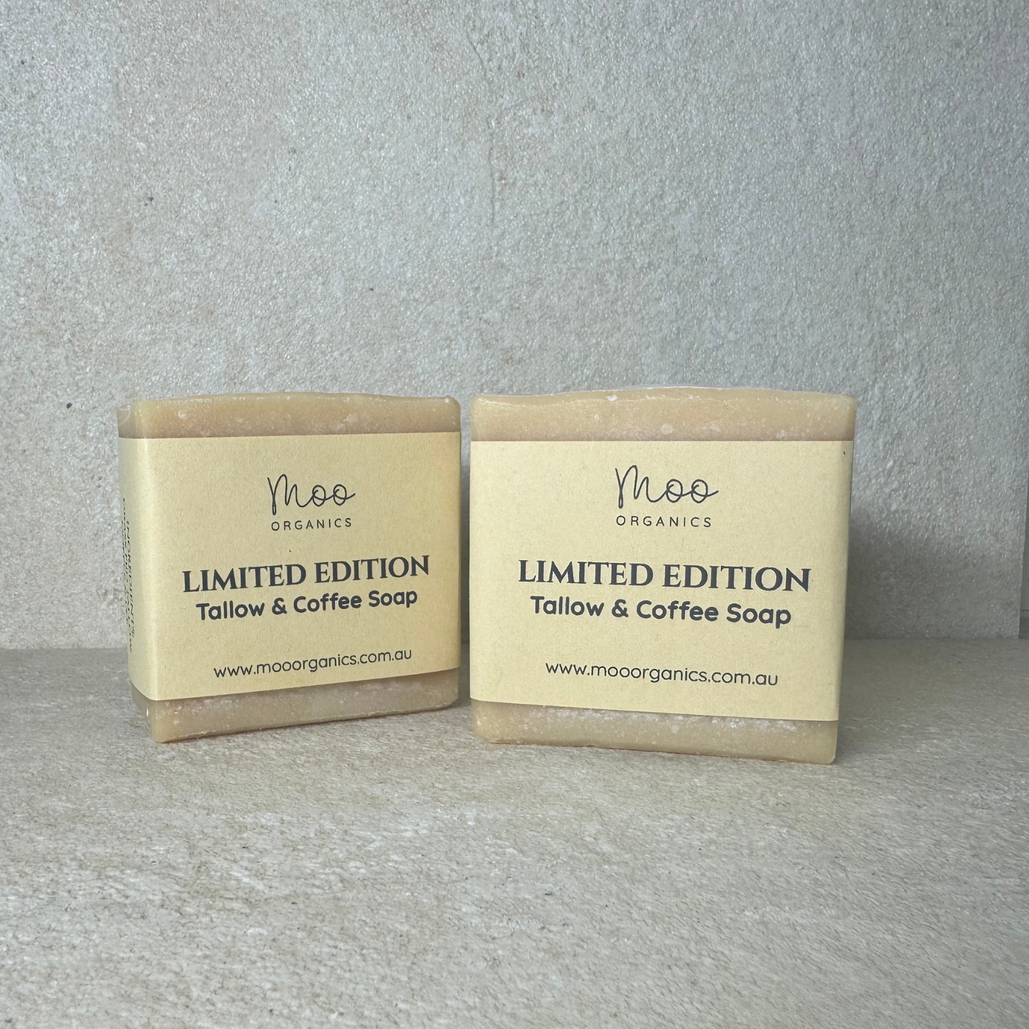 Two bars of limited edition tallow and coffee soap from Moo Organics on a gray background